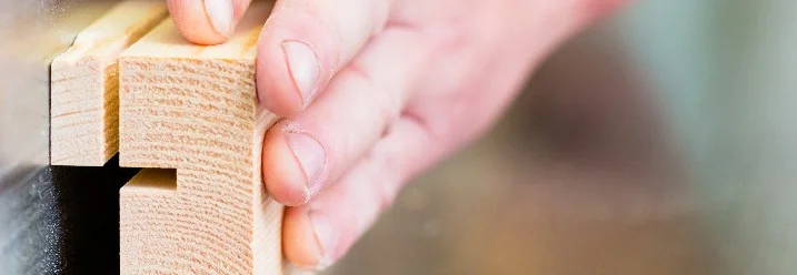 Hand führt Holz an Säge
